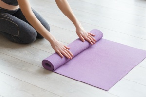 women rolling up mat after Savasana