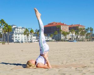 women in the sand holding a pose with her legs pointed in the air