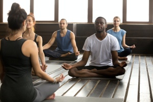 Group of young people learning from a new yoga teachers