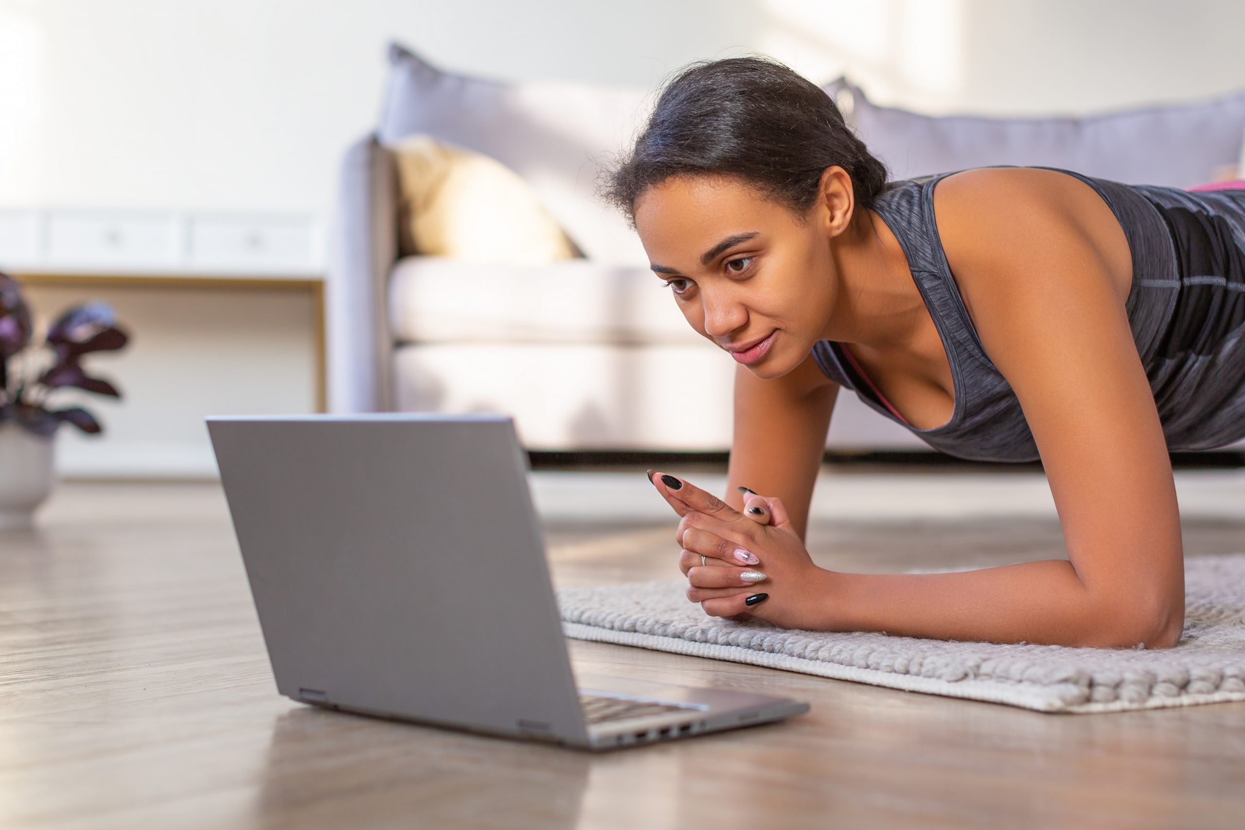 yogi holding plank while looking at a laptop to do yoga online