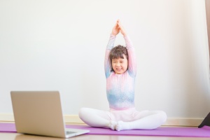 girl watching video of someone teaching children yoga