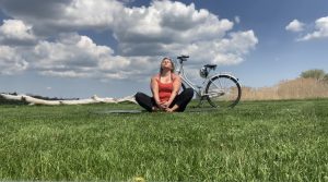 Girl in field gazing at sky with bike