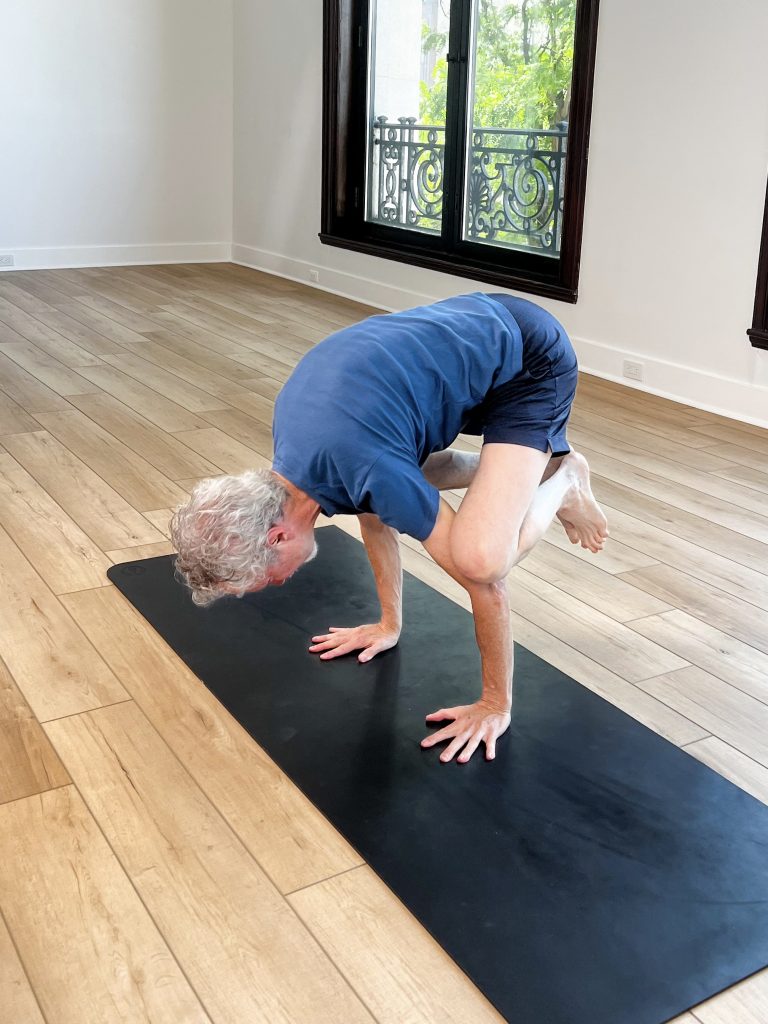 Man on a mat doing crow pose