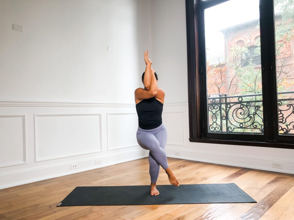 A girl in eagle pose on a yoga mat