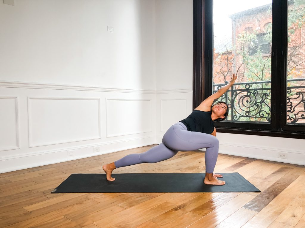 A girl in low lunge twist on a yoga mat 