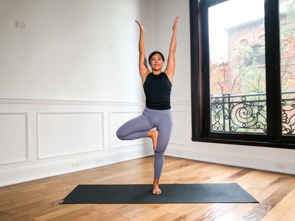 girl in tree pose with arms extended up high