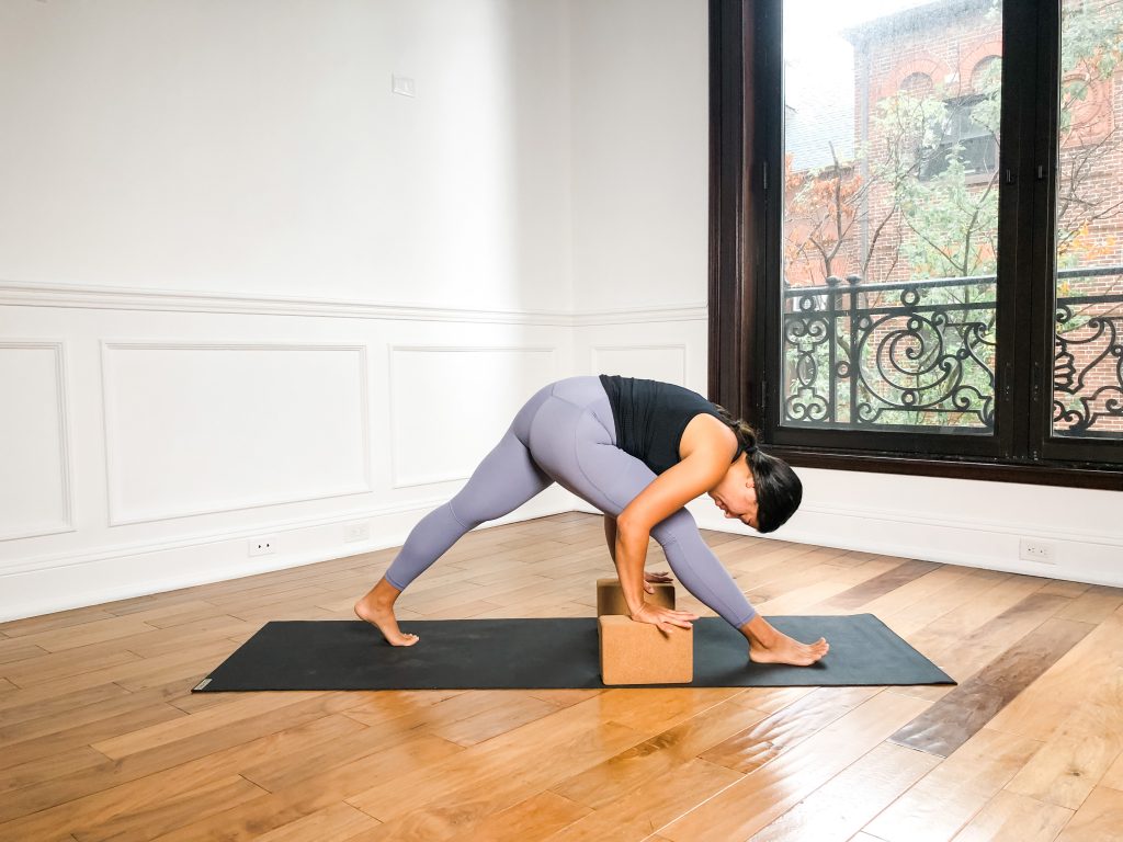 Person in Pyramid Pose with their hands on blocks on a black yoga mat