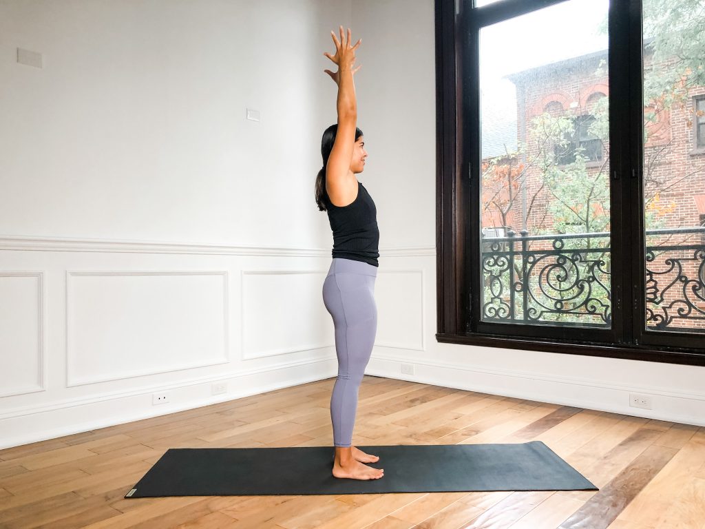 Woman reaching her arms straight up by her ears for Upward Hands posture in yoga