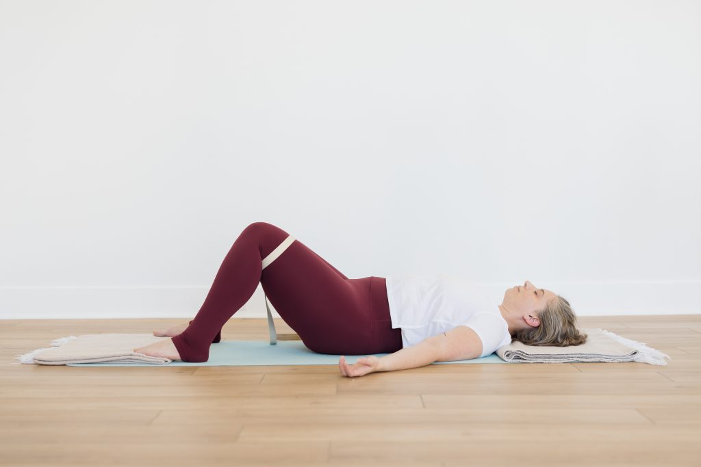 Alex lying on her back, knees bent with strap around the lower thigh