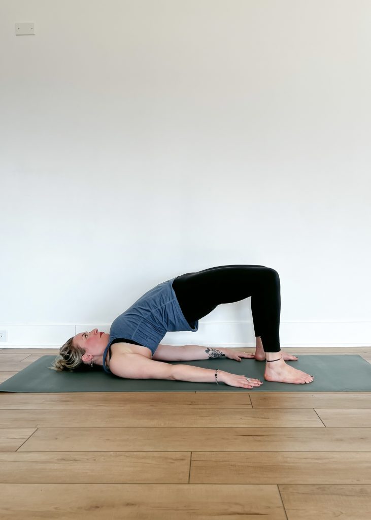 Human in bridge pose on a yoga mat