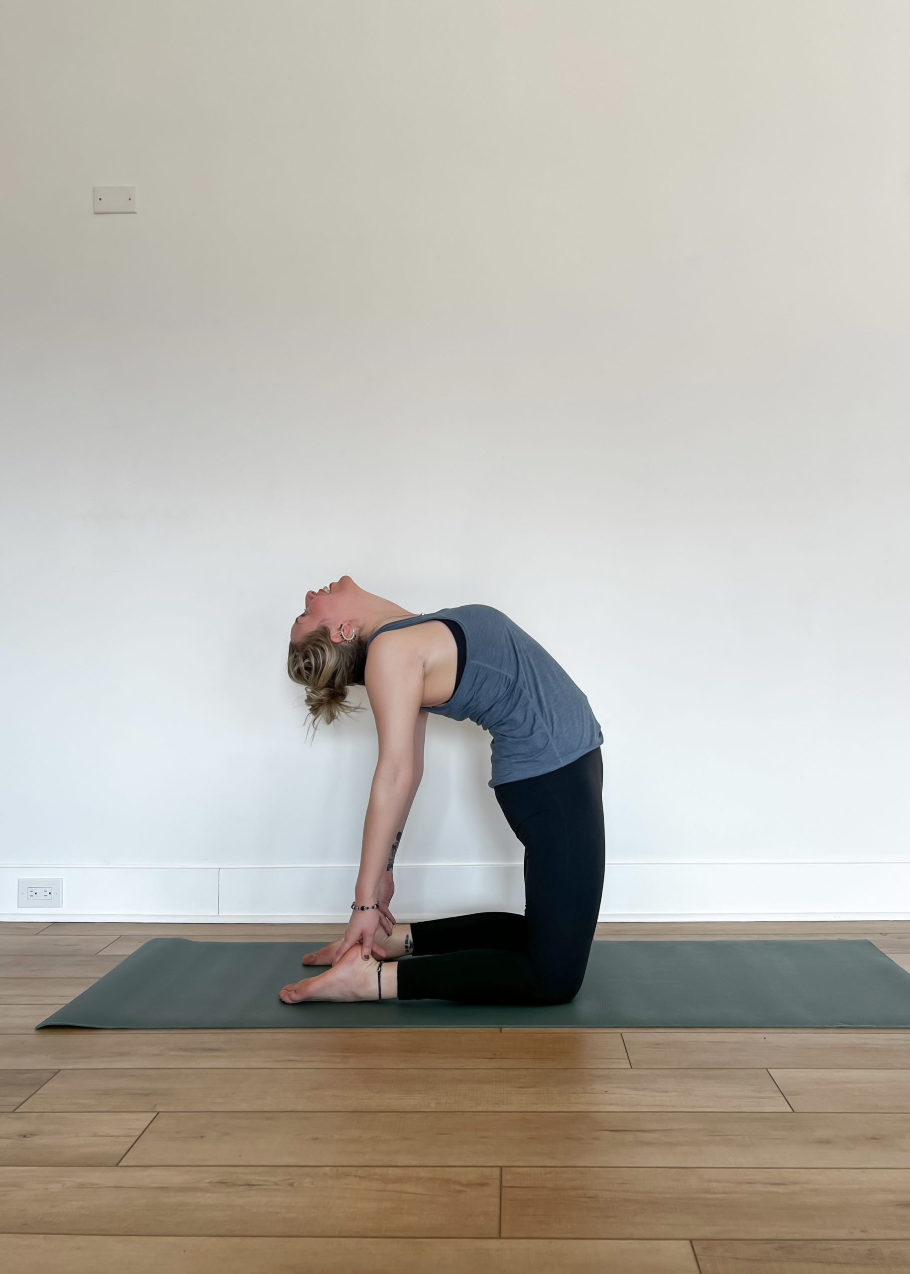 Human in Camel Pose on a green yoga mat