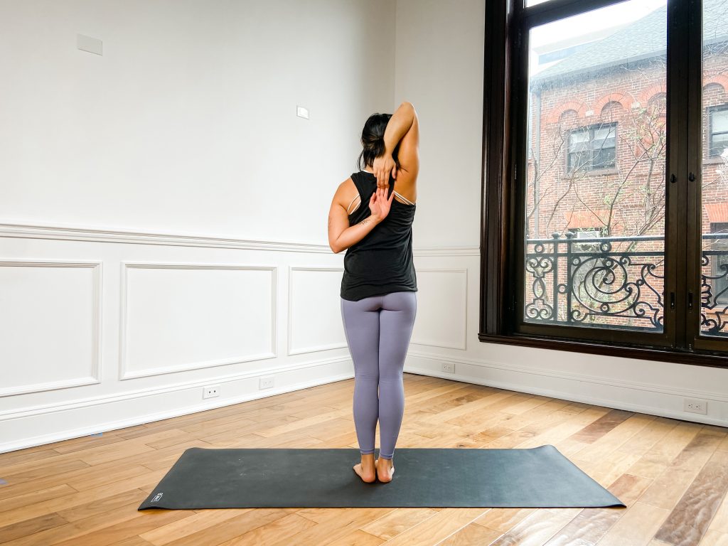 Person doing Cow Face pose arms on a yoga mat