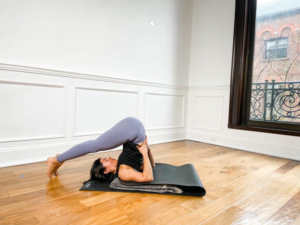 Person in purple leggings in plow pose