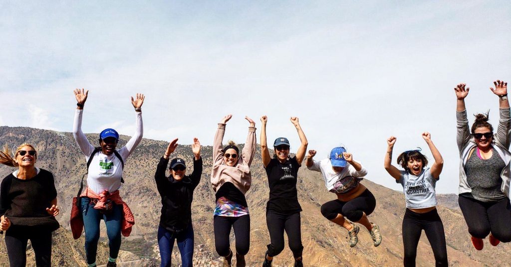 A row of yogis jumping in the air with their arms up on a yoga retreat in another country