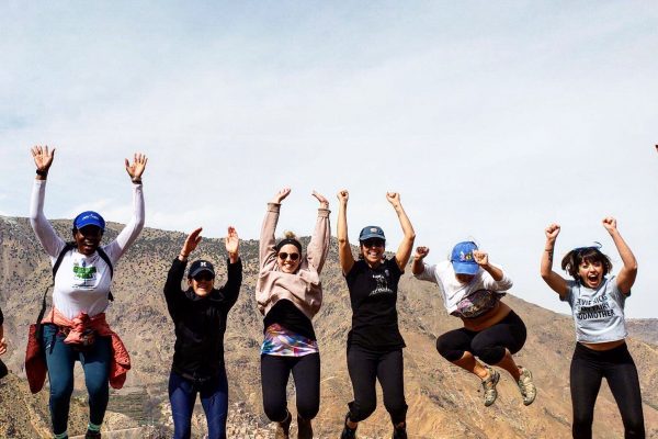 A row of yogis jumping in the air with their arms up on a yoga retreat in another country