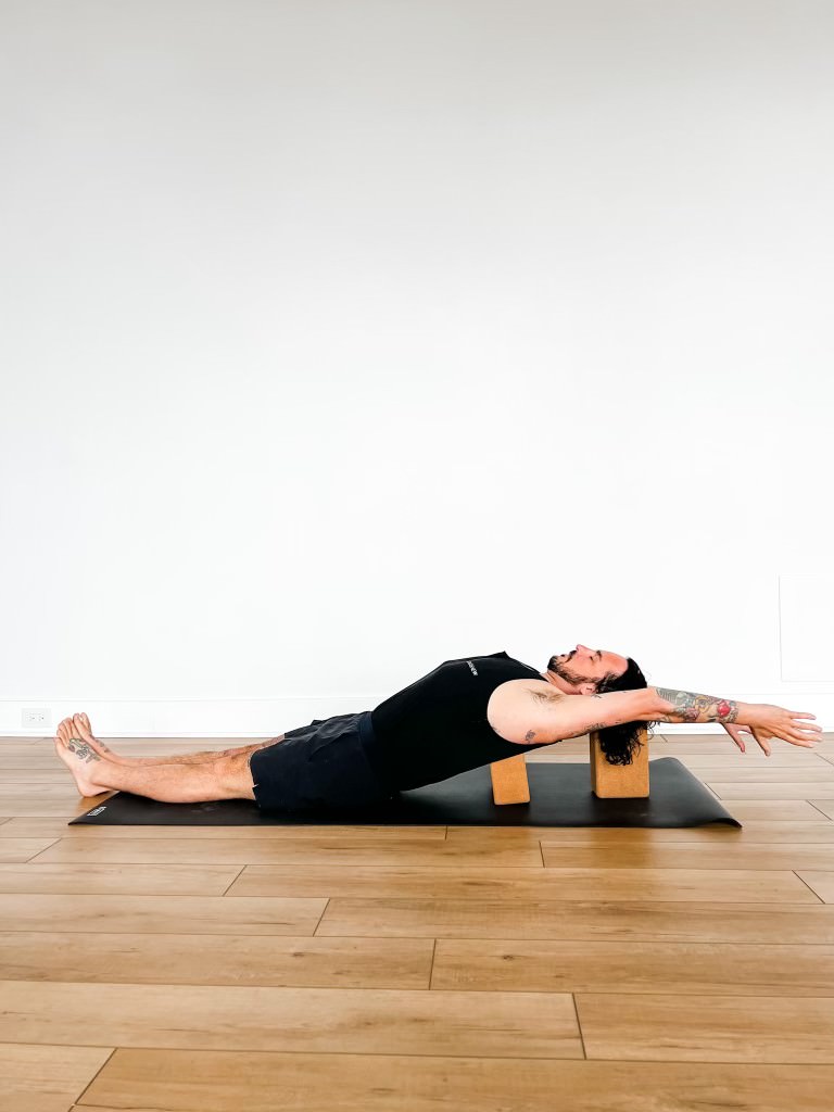 Patrick in supported fish pose with arms overhead