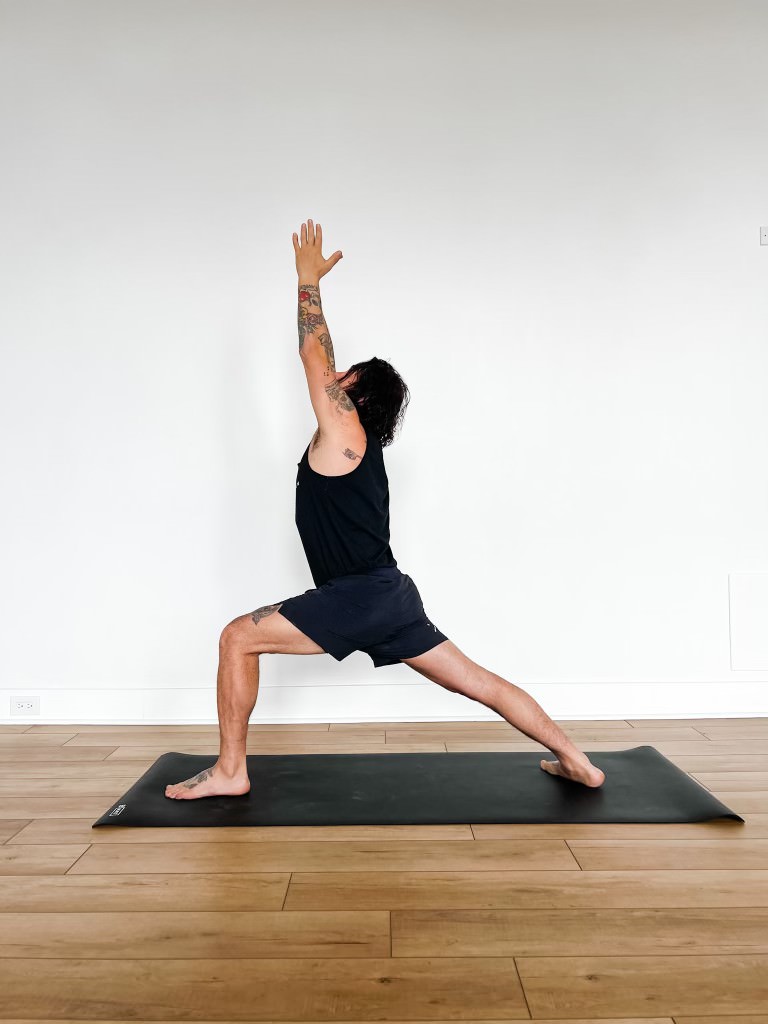 Patrick in warrior 1 pose on a yoga mat