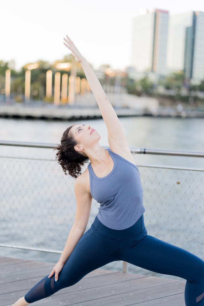 Woman outside, in front of water doing Peaceful Warrior